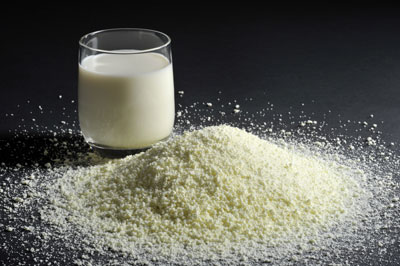 Glass of milk with milk powder in a pile next to the glass