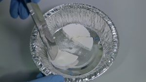 Image of compacted milk powder being broken with a spatula